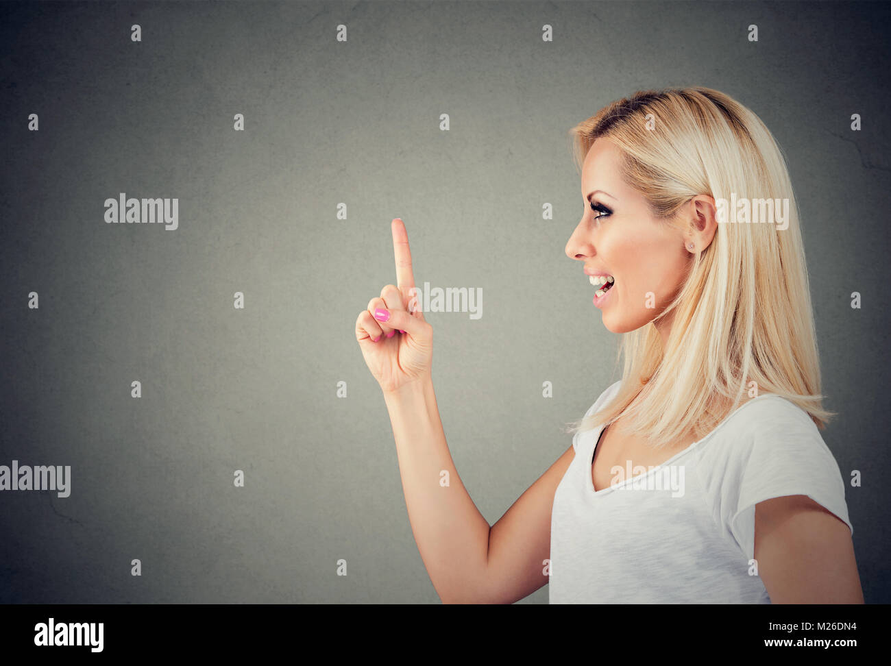 Side view of young content blonde holding forefinger up having new idea. Stock Photo