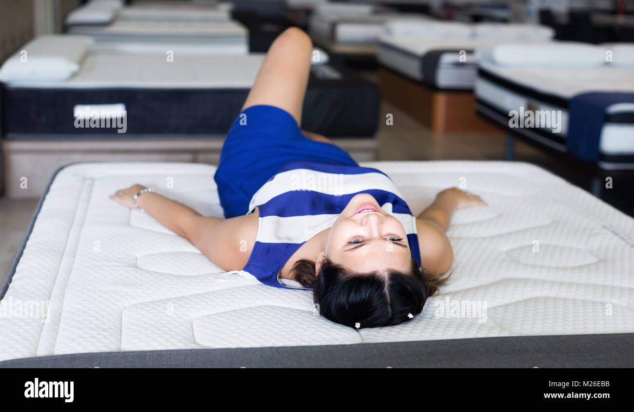 Young girl lying enjoing on softy mattress in the shop Stock Photo