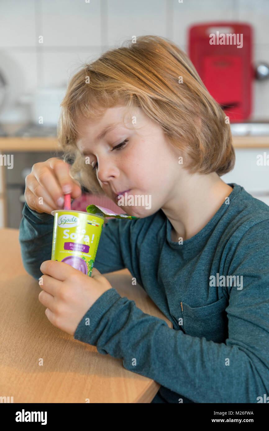 Boy, 7 years old, tastes vegan food, soy fruit yogurt substitute, Stock Photo