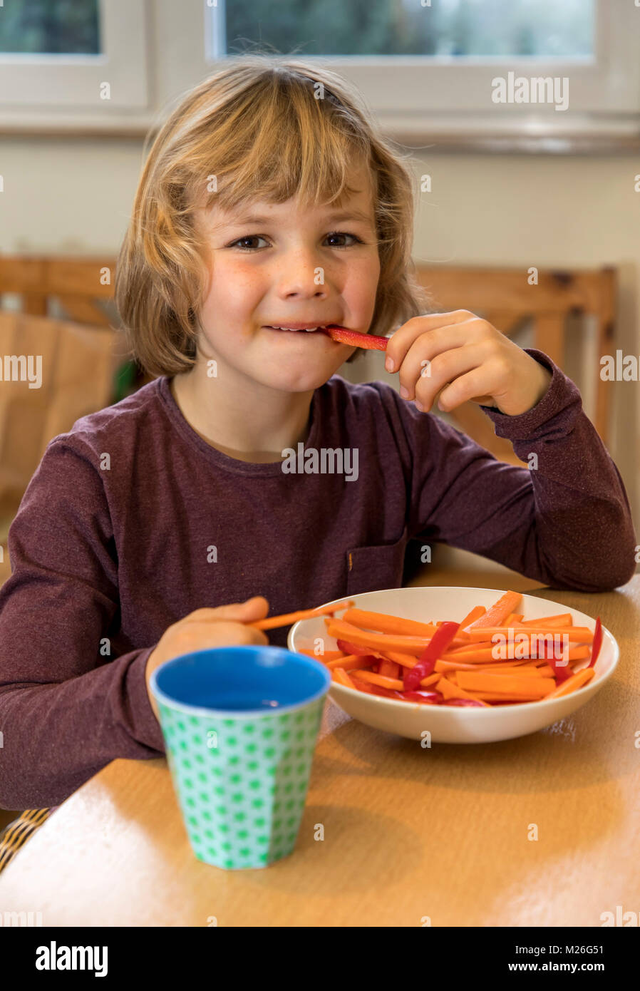 Boy, 7 years old, eats vegetables, peppers and carrots pieces Stock