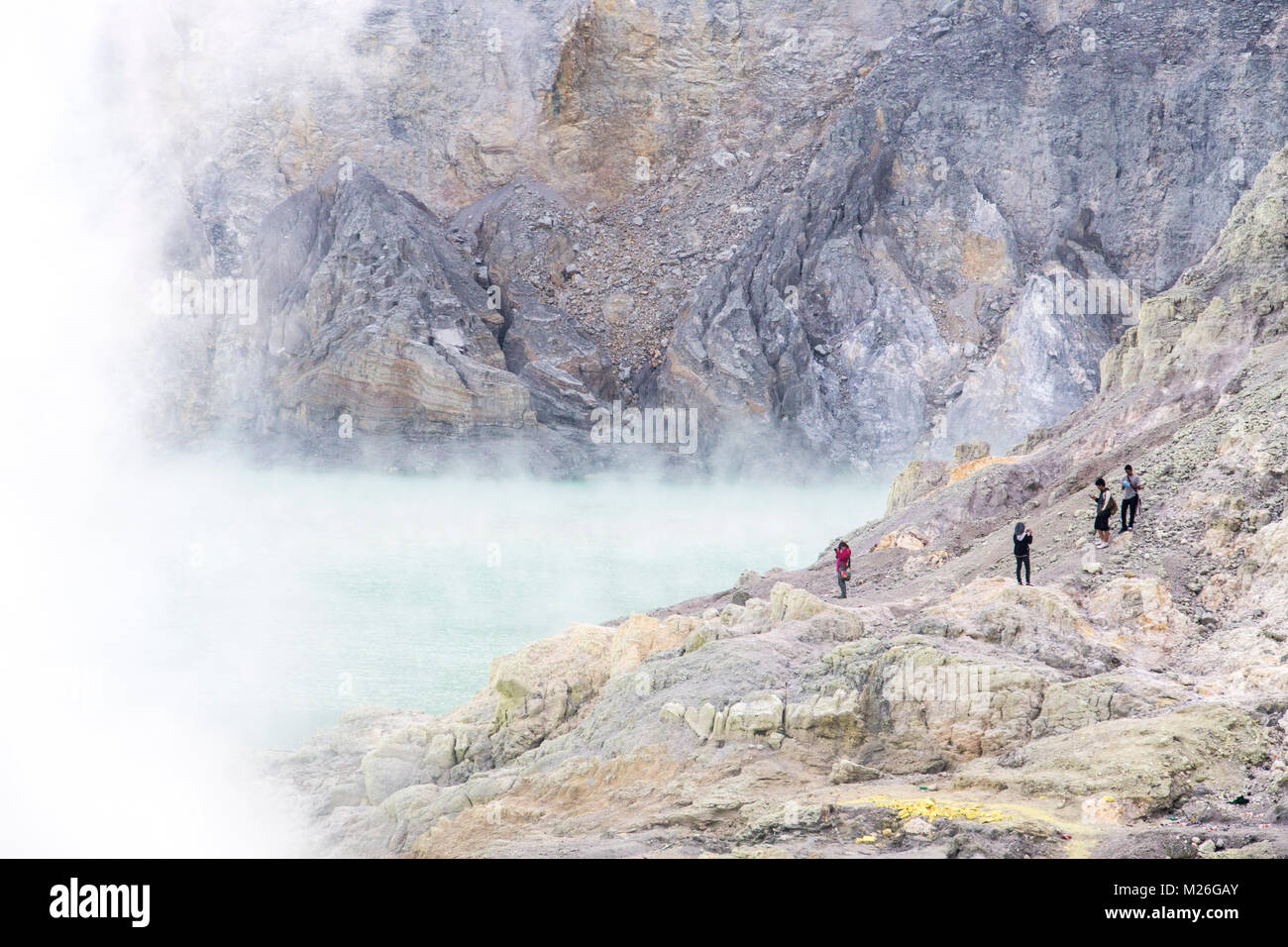 Tourists view the largest highly acidic crater lake in the world inside Kawah Ijen, a composite volcano in East Java, Indonesia. Stock Photo