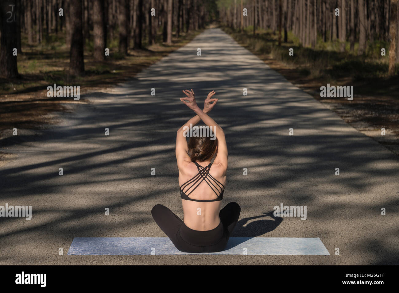 woman sitting on a yoga mat meditating in the middle of a road in a ...