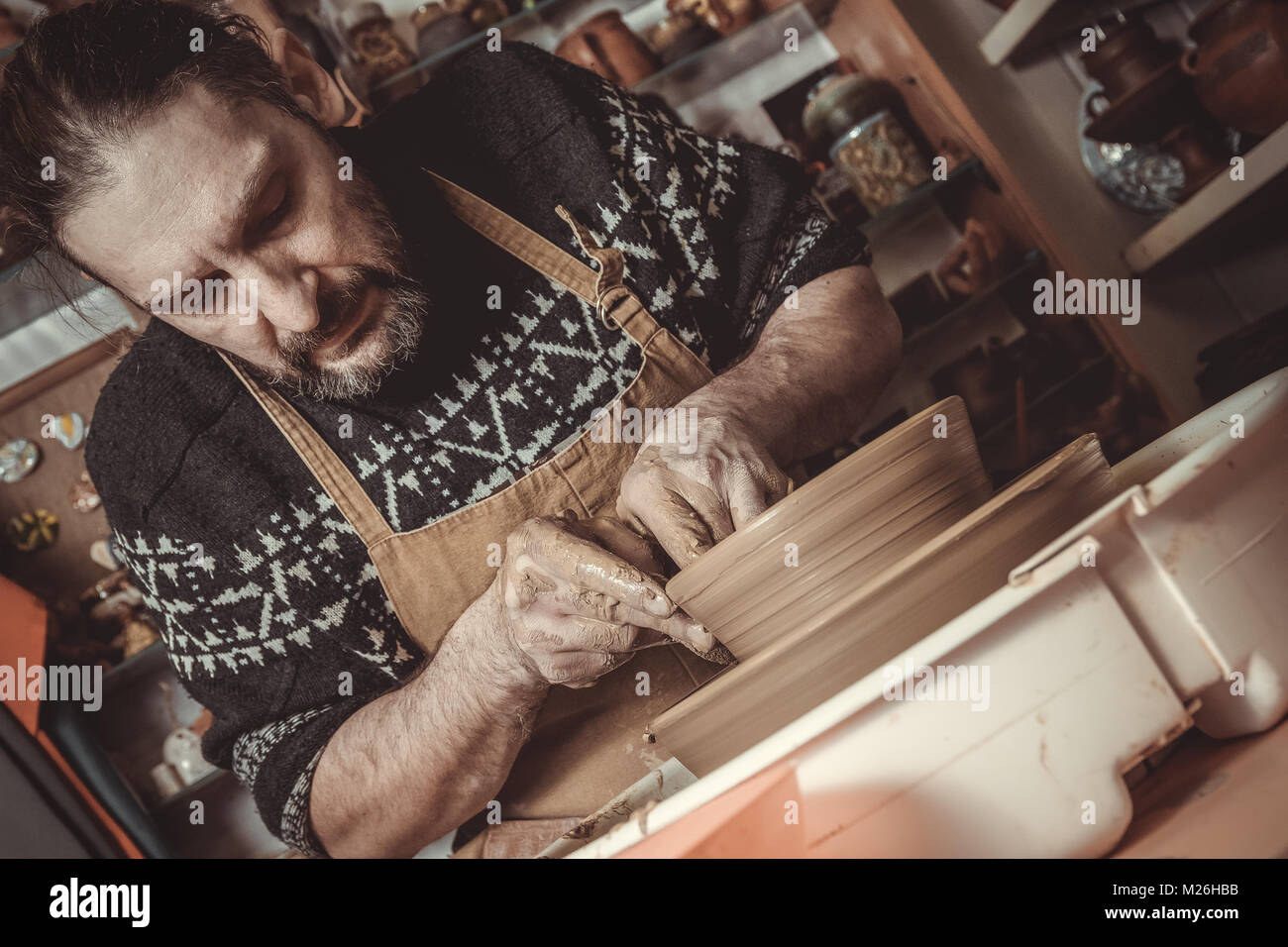 elderly man making pot using pottery wheel in studio Stock Photo