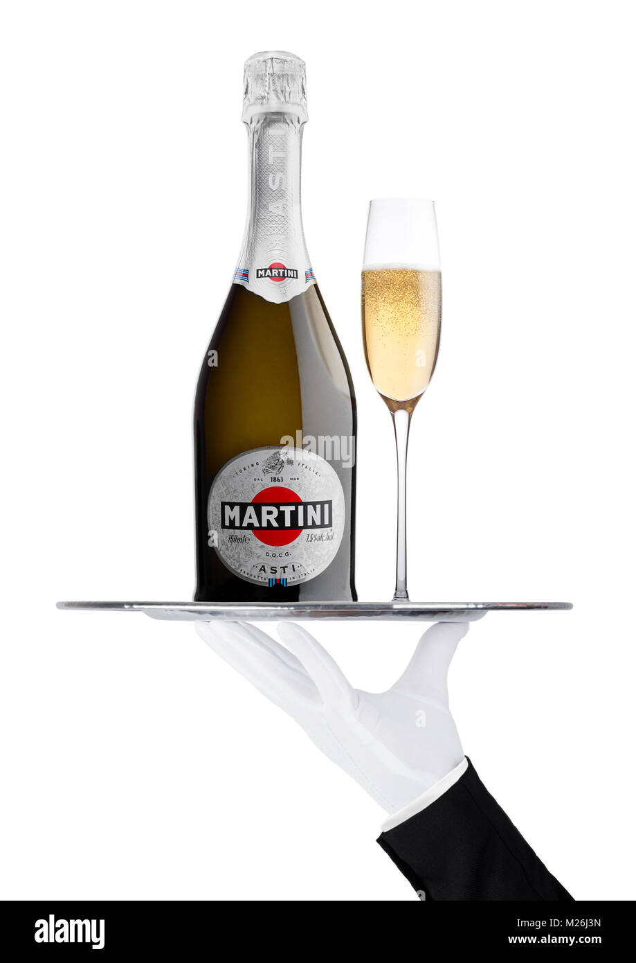 LONDON, UK - November 24, 2017: Hand with glove holds tray with Martini Asti champagne bottle and glass on white background. Produced in Italy Stock Photo