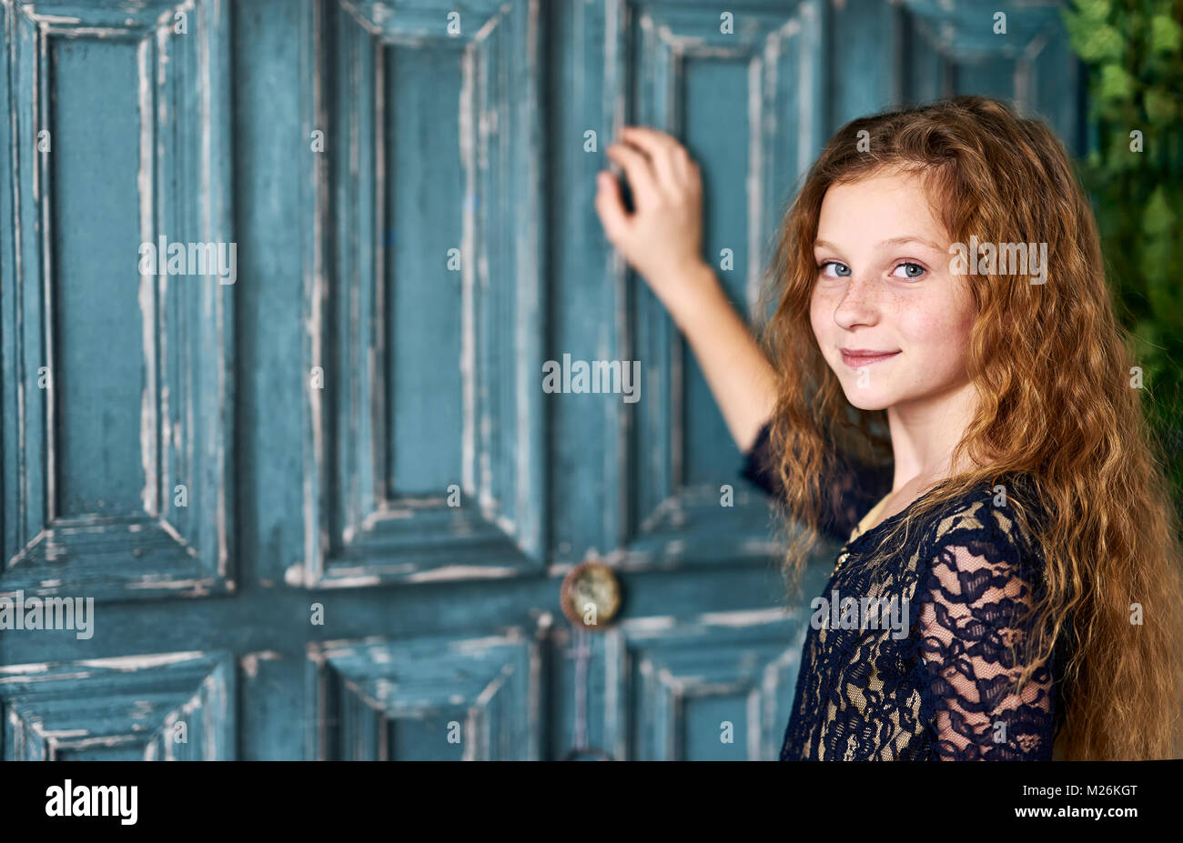 Red-haired little girl in front of blue door Stock Photo