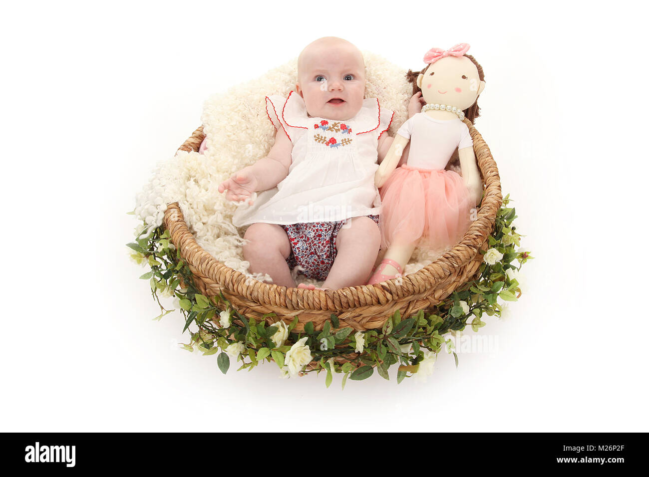 beautiful 3 month old baby girl happy playing in basket with dolly Stock Photo