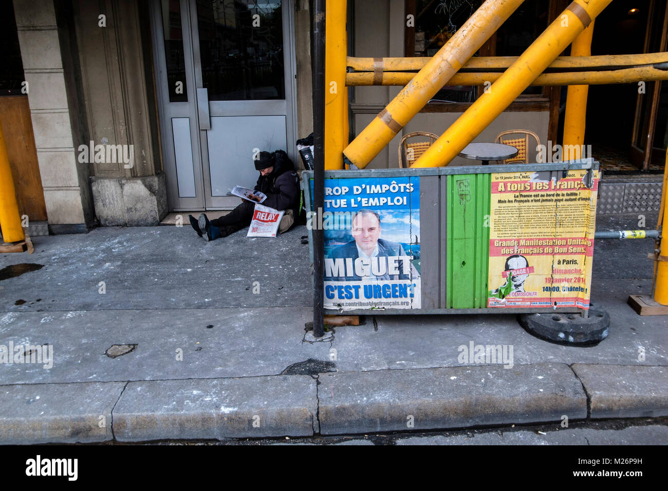 PARIS FRANCE- PARIS POVERTY - HOMELESS READING A NEWS PAPER ON THE PAVEMENT - SANS ABRI DANS LA RUE - FRENCH CONTEST POSTERS  © Frédéric BEAUMONT Stock Photo