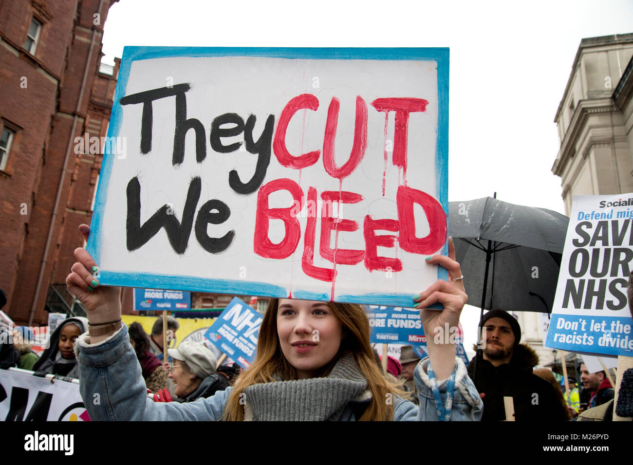 Demonstration called by the People's Assembly in support of the NHS (National Health Service}. A young woman holds a placard saying 'They cut we bleed' Stock Photo