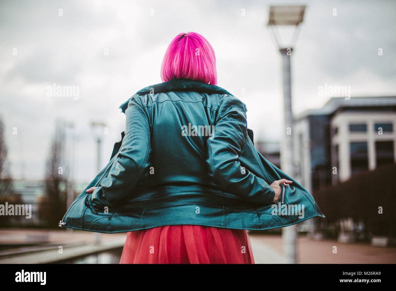 Portrait of a young woman with pink hair looking away with her jacket open. Stock Photo