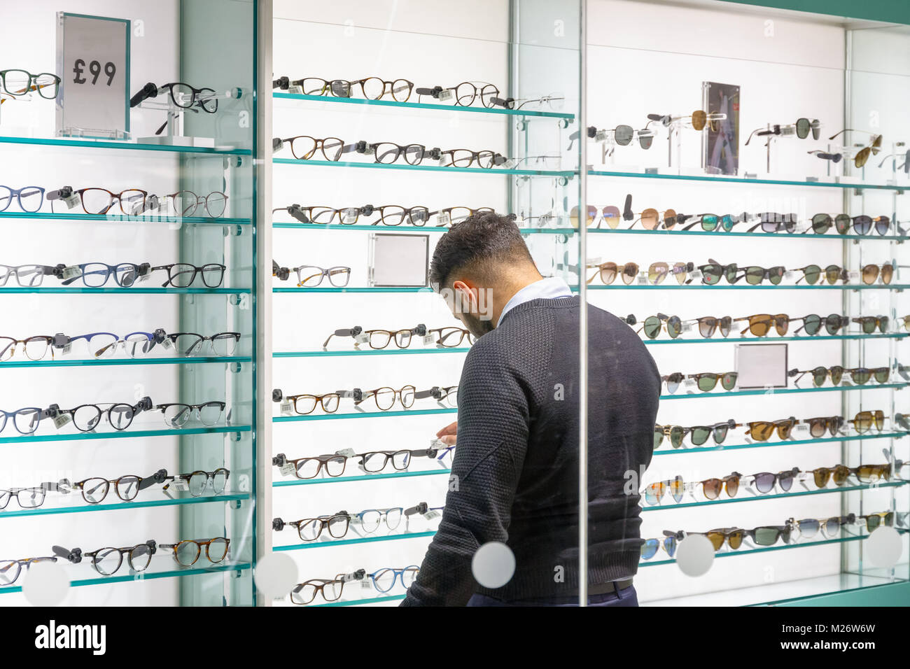 Back view of a customer browsing glasses at an opticians in Canary Wharf,  London Stock Photo