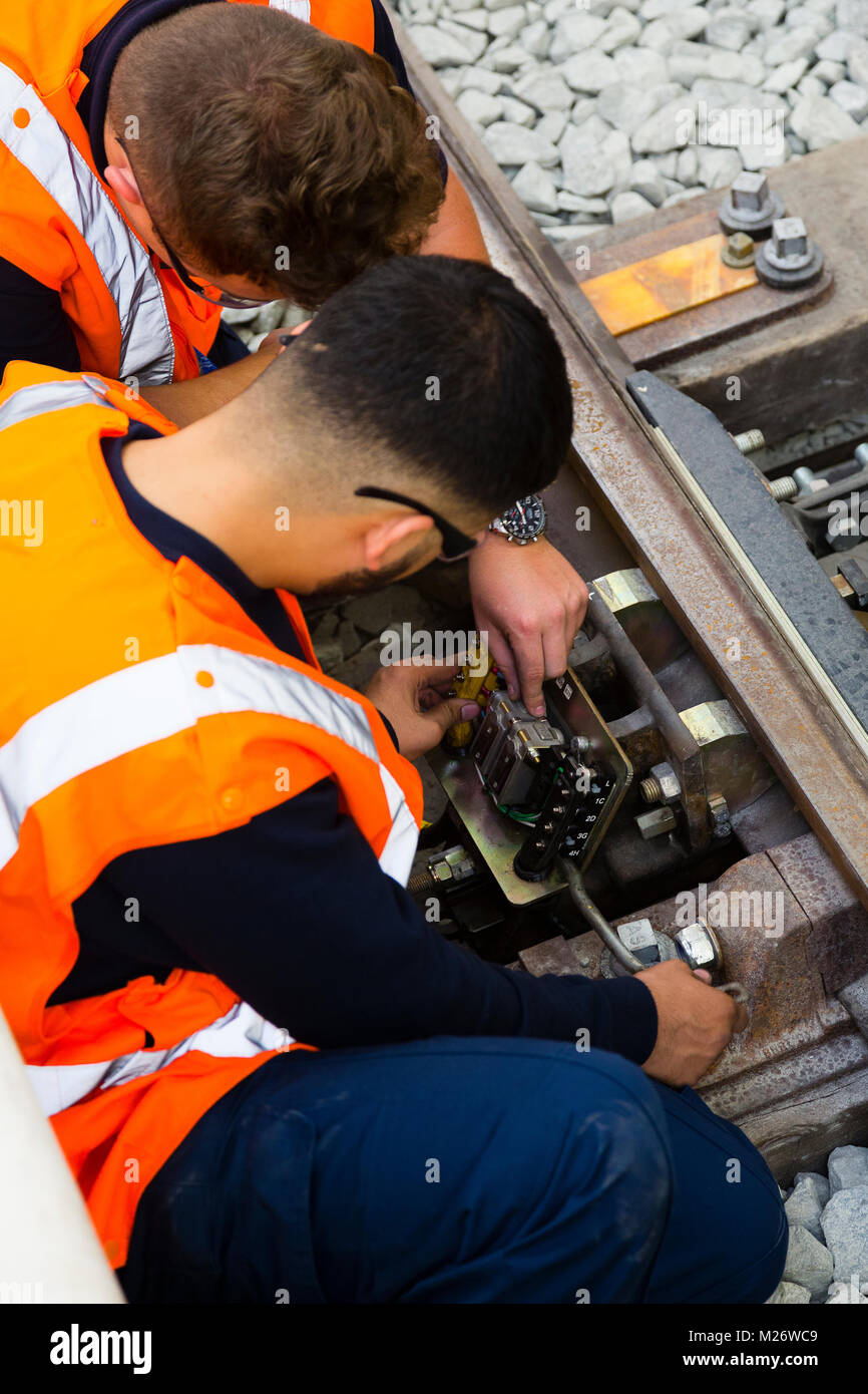 Two young men work on a junction box on a railway line. Stock Photo