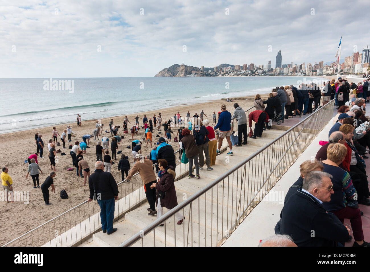Seniors keeping fit on the beach in Benidorm, Spain. Men women oap's, elderly fitness class spectators watching and joining in. Stock Photo