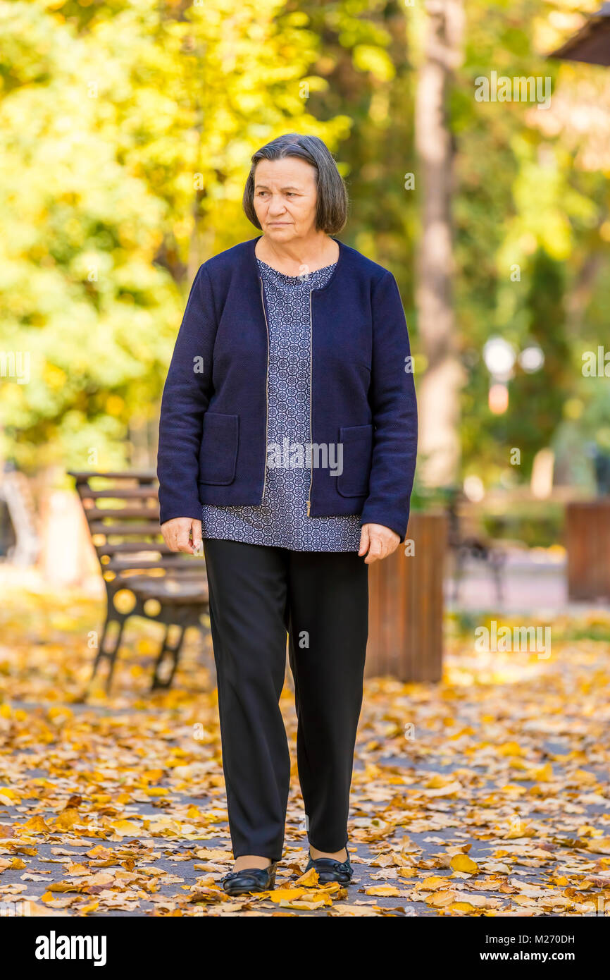 Depressed senior woman thinking worried outdoors in park. Stock Photo