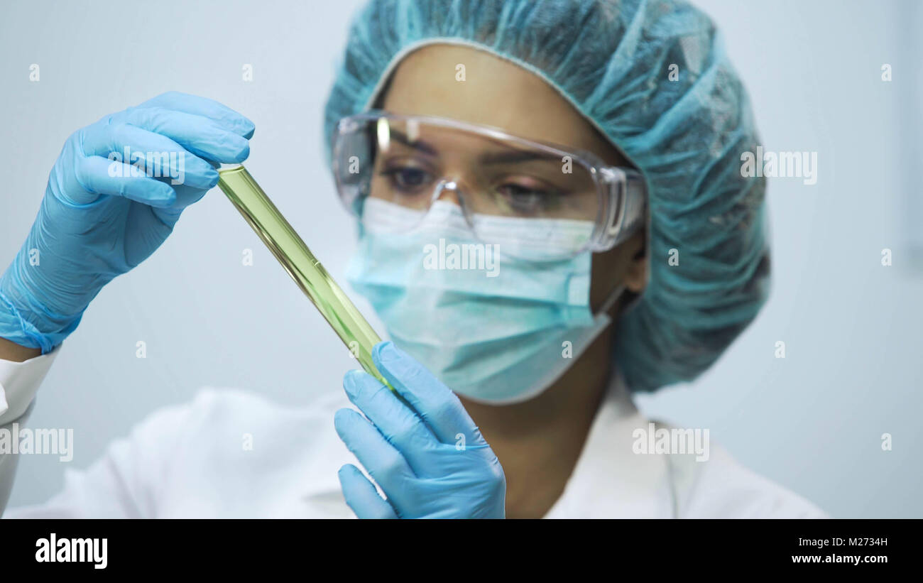 Attractive lab assistant analyzing biomaterial in tubes, biochemical research Stock Photo