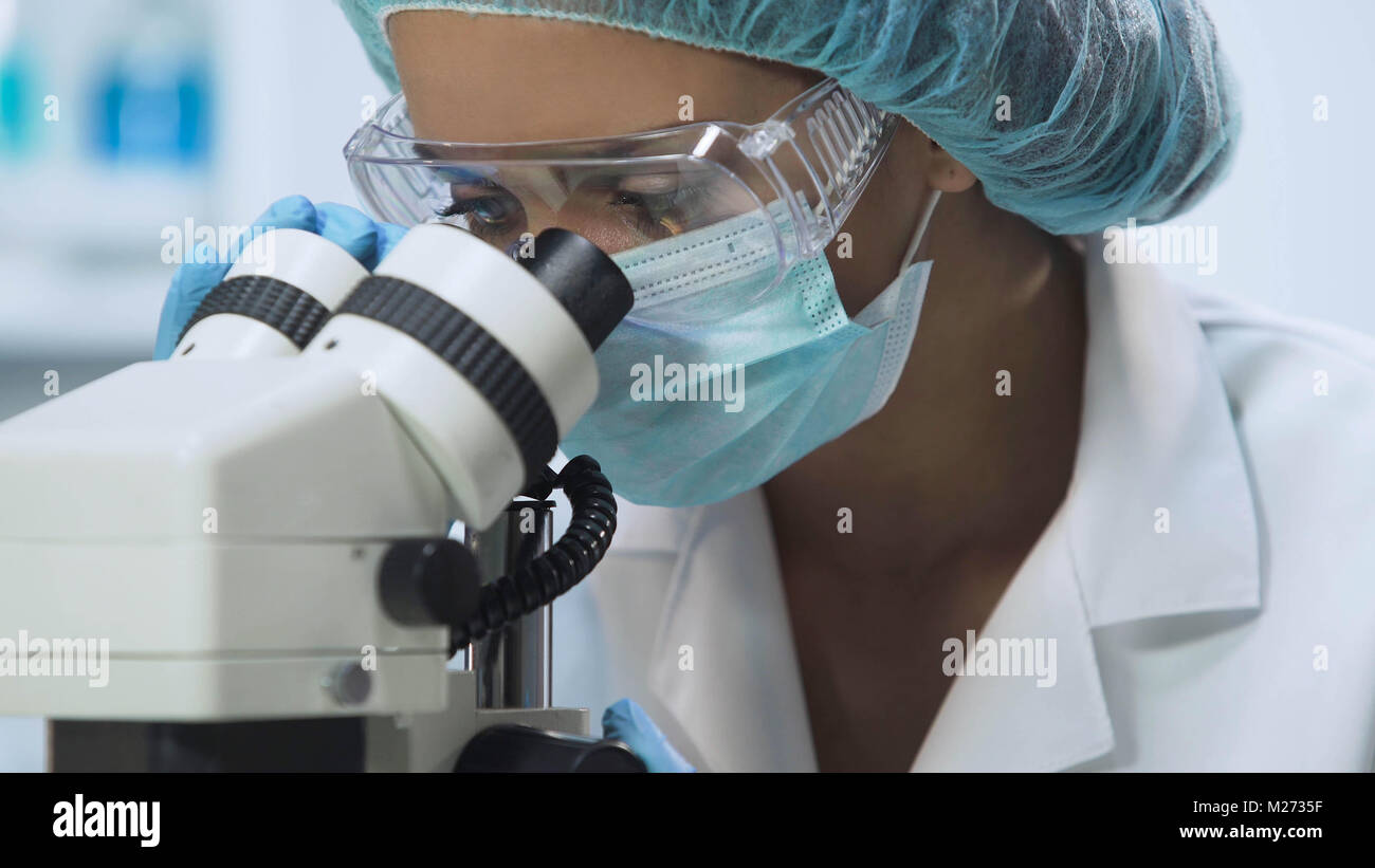 Young female scientist using microscope for microbiological analysis, medicine Stock Photo