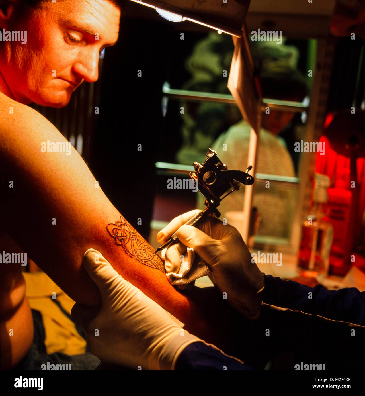 Tattoo artist Marc Saint tattooing a celtic design on a clients arm, London, tattoo parlor, archive photograph 1990 Stock Photo