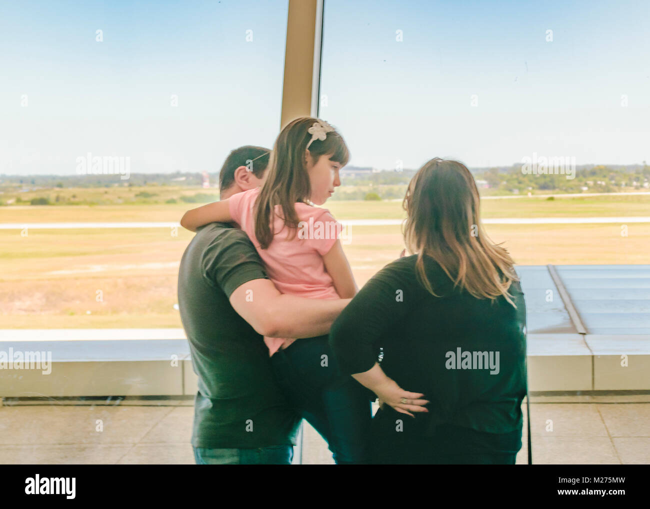 MONTEVIDEO, URUGUAY, DECEMBER - 2017 - Back view of family watching the runway through window at aeropuerto internacional de carrrasco, Montevideo, Ur Stock Photo