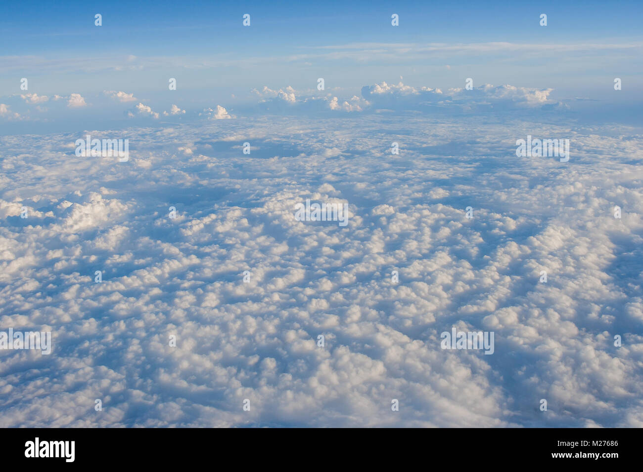 Clouds and blue sky view out from window of airplane fying over earth ground. Stock Photo