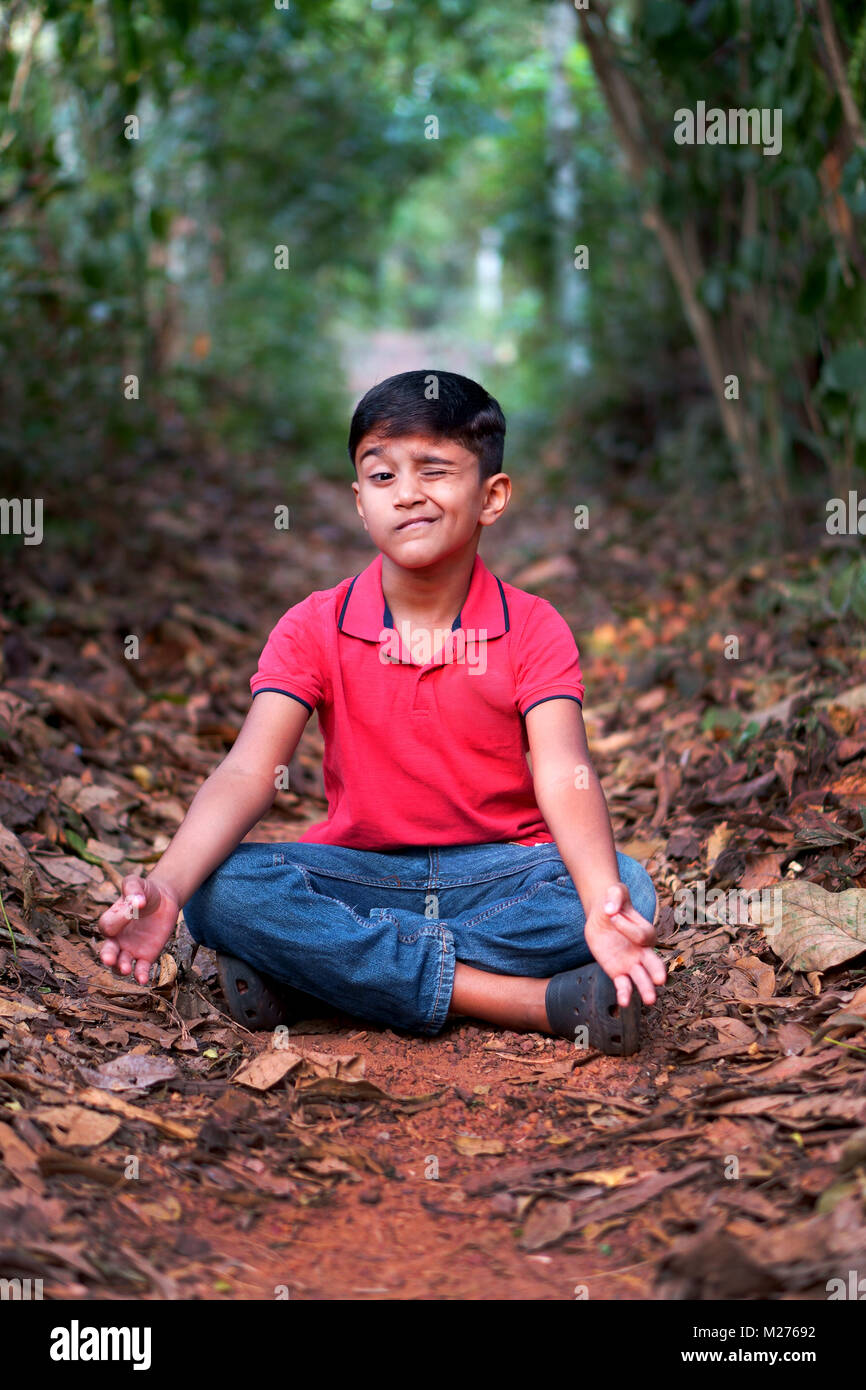 Young boy doing yoga in woods winking Stock Photo