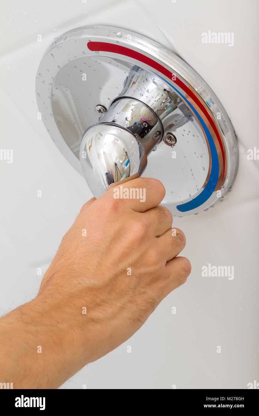 Human Hand switches a Shower faucet cold and hot water in the bathroom Stock Photo