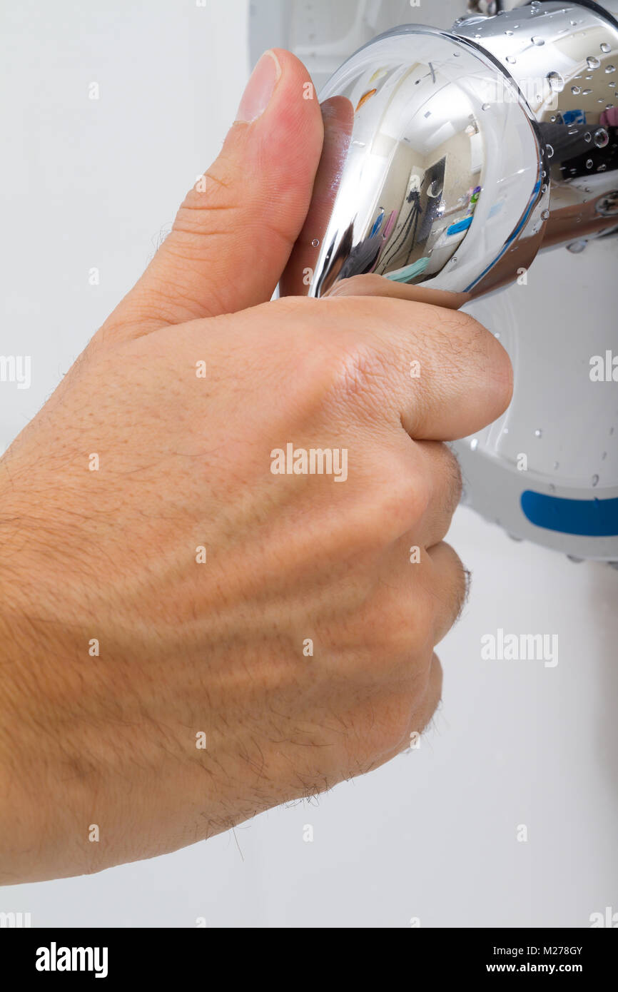 Human Hand switches a Shower faucet cold and hot water in the bathroom Stock Photo