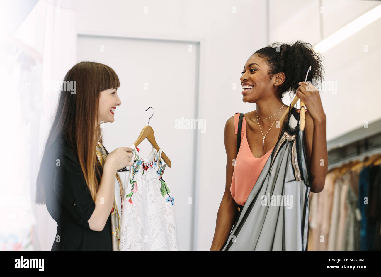 Happy customer having a look at a dress in a boutique. Woman entrepreneur showing designer clothes to a customer. Stock Photo