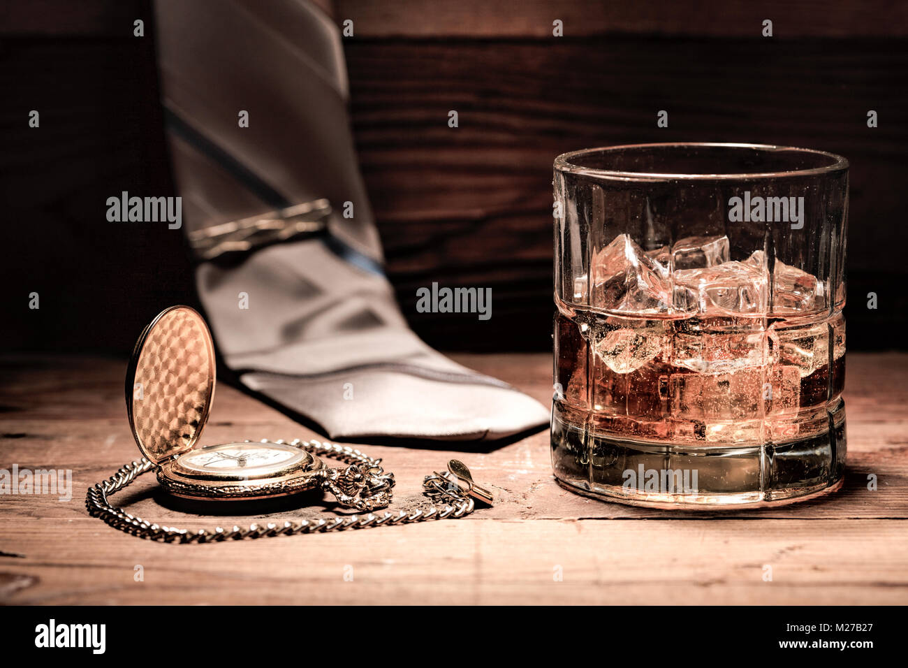 A conceptual image of aa glass of liquor, a pocket watch, and a neck tie. Stock Photo