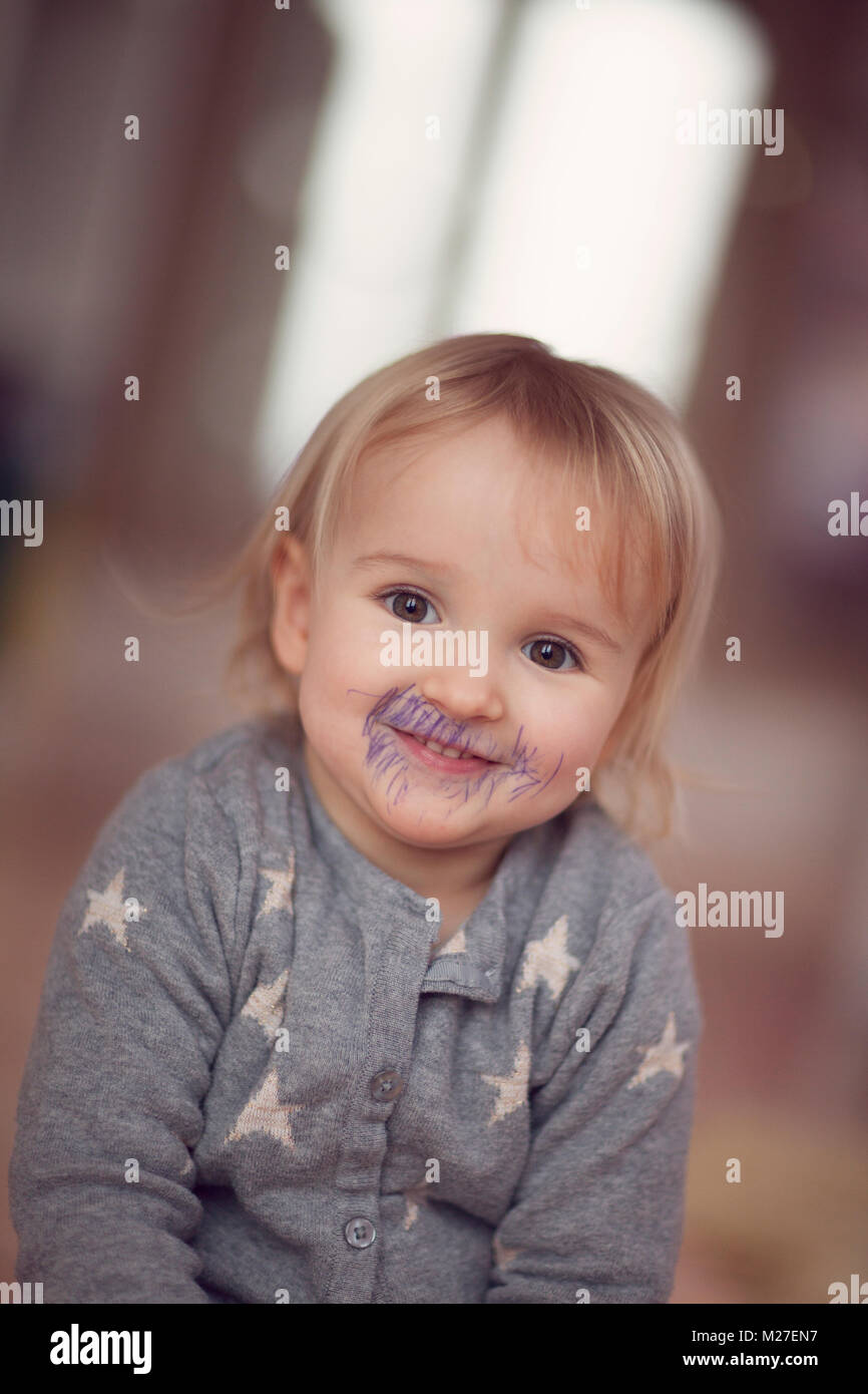 Mischievious, smiling toddler with biro drawn on face Stock Photo