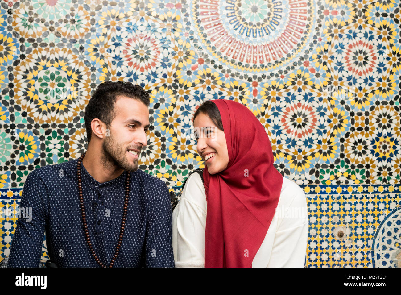 Muslim couple in relationship talking and smiling in front of arabesque oriental decoration Stock Photo