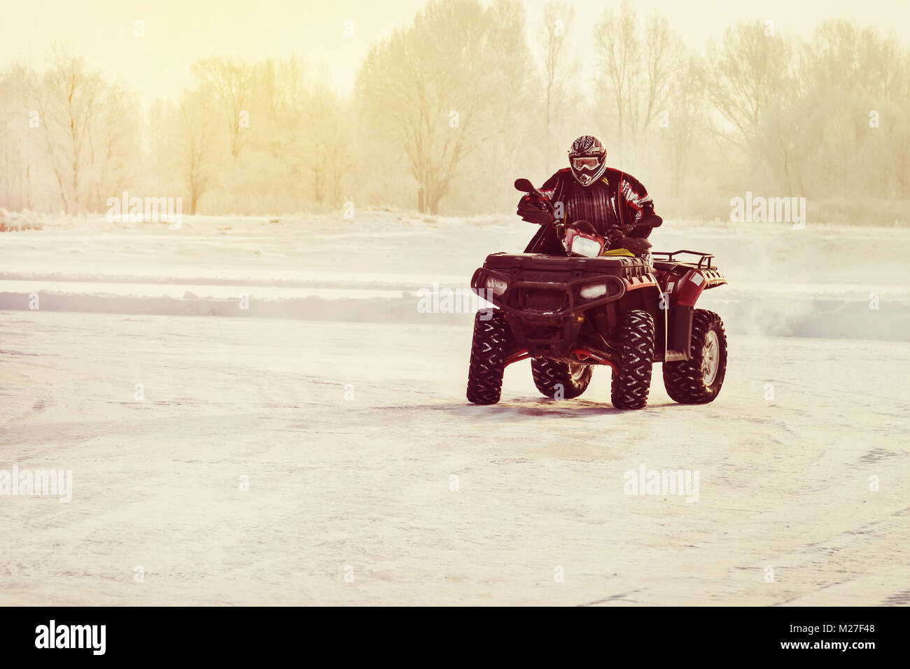 Quad bike driver riding over a frozen lake. ATVs are riding in the