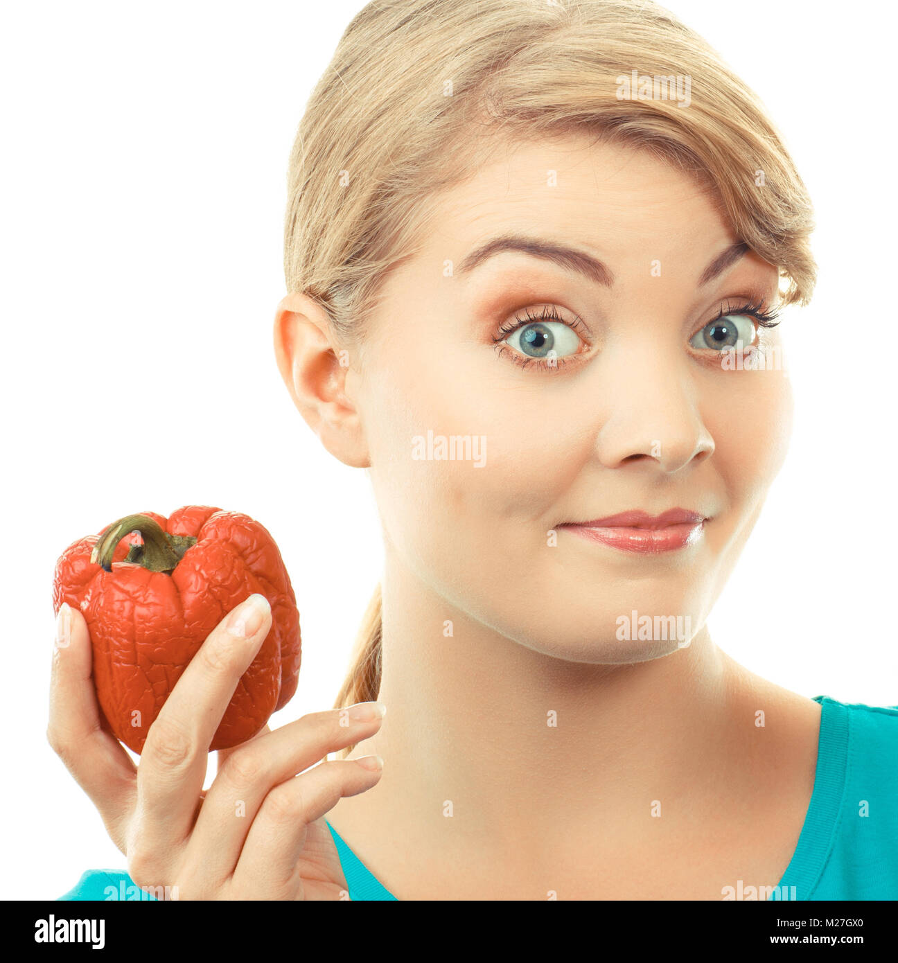 Unhappy and disgusted woman holding in hand old wrinkled peppers, concept of unhealthy food Stock Photo