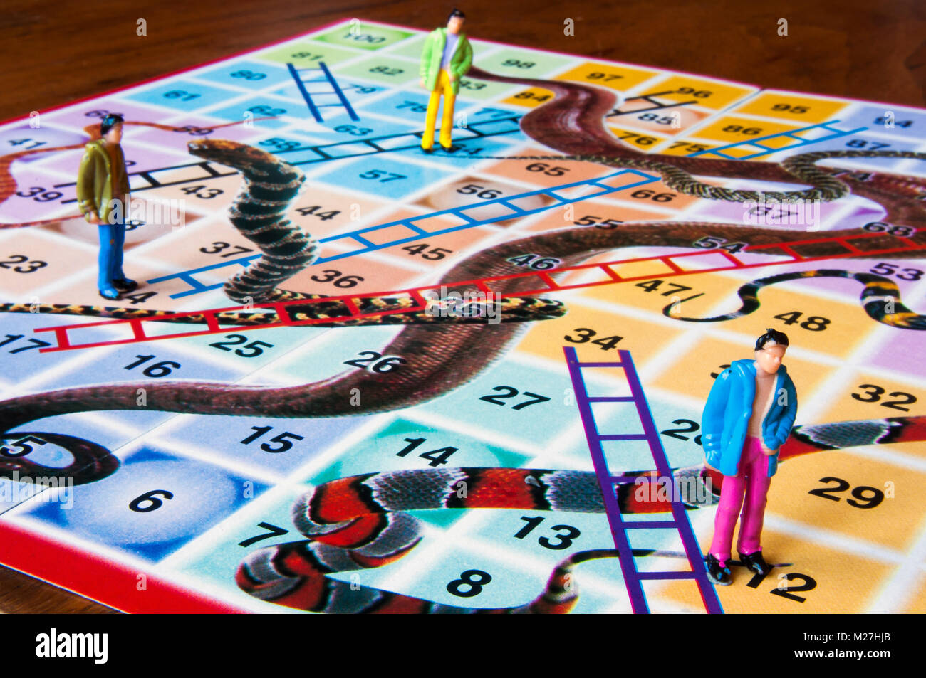 Snakes and ladders board with miniature human figures in studio setting, Melbourne, Australia Stock Photo