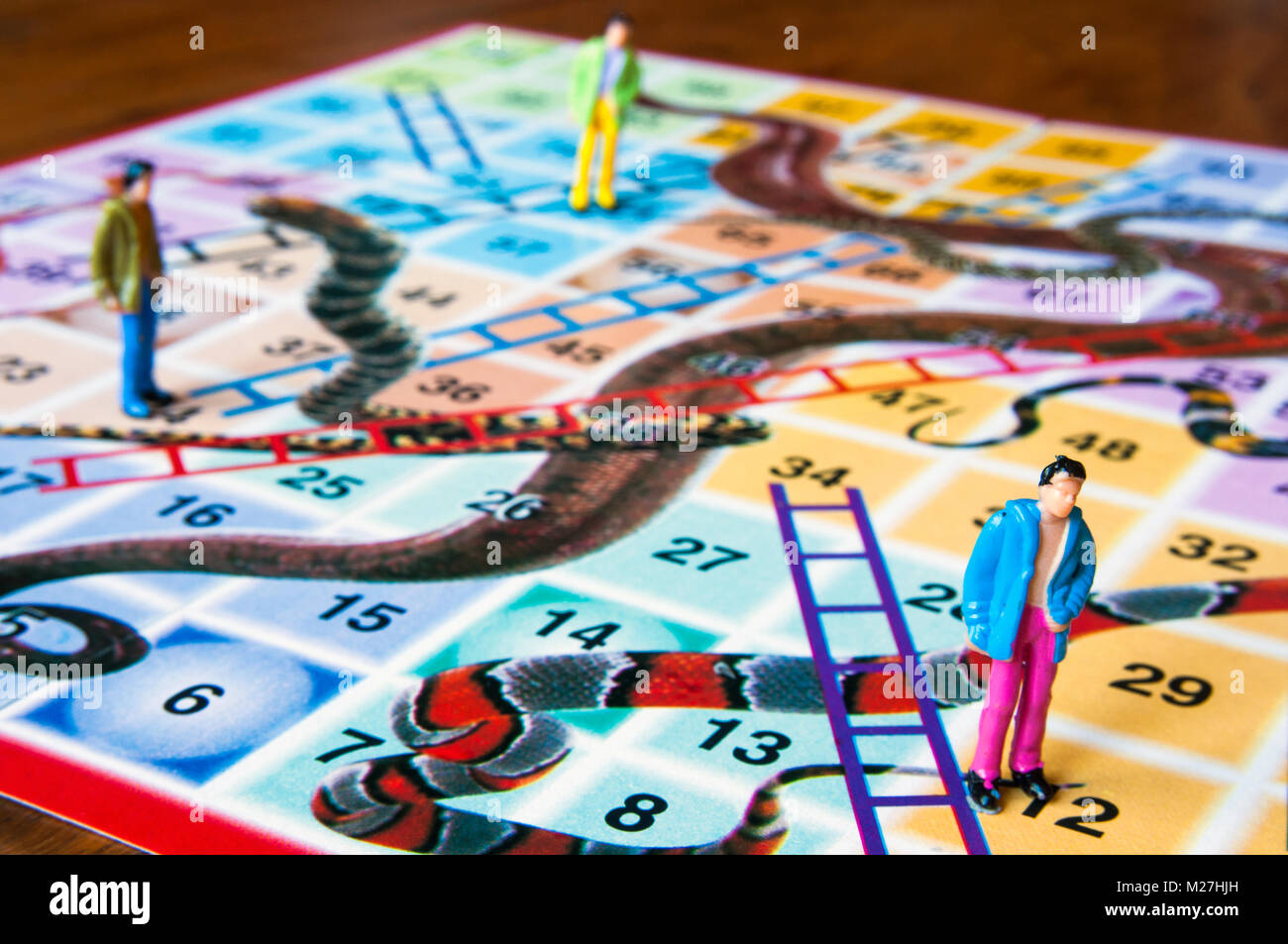 Snakes and ladders board with miniature human figures in studio setting, Melbourne, Australia Stock Photo