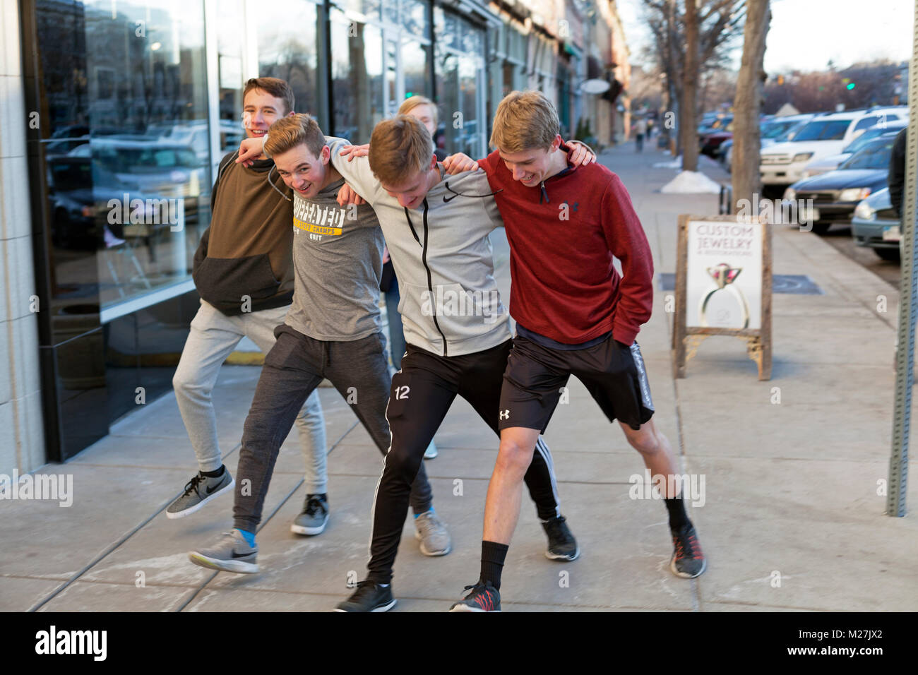 A group of friends locks arms and sidestep down the sidewalk in Fort