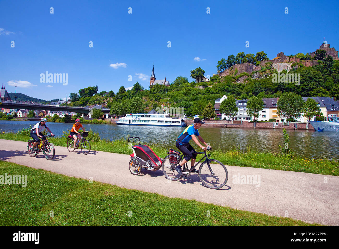 Cyclists on cycleway at riverside, excursion ship on the Saar river, above the castle, Saarburg at the Saar river, Rhineland-Palatinate, Germany Stock Photo
