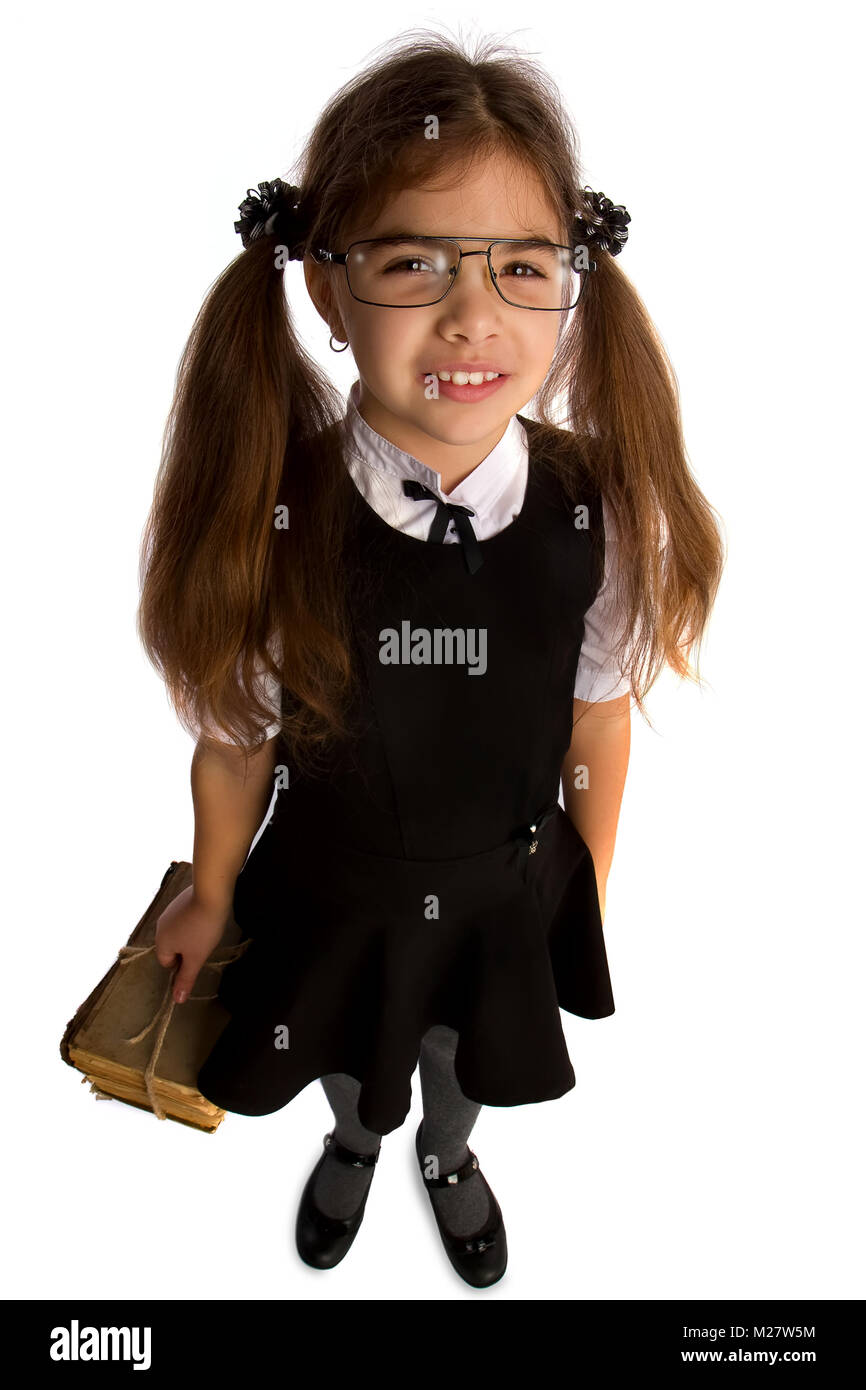 A little schoolgirl in glasses holds a stack of old books tied with a rope and looks up her head Stock Photo