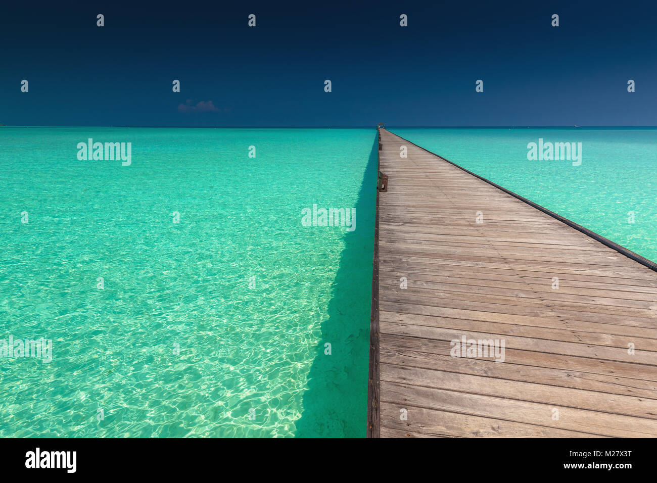 Wooden long jetty over lagoon with amazing clean azure water, Maldives ...