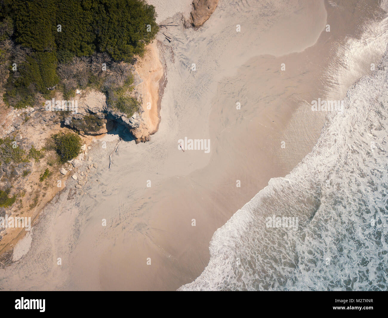 Aerial drone view at a beach section of Riviera Nayarit, Mexico, with a woman lying on her back tanning. Stock Photo