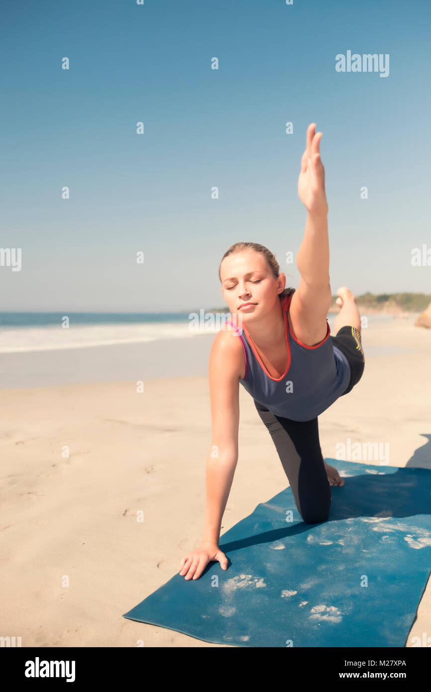 Caucasian woman exercising yoga at a beach, eyes closed. Stock Photo