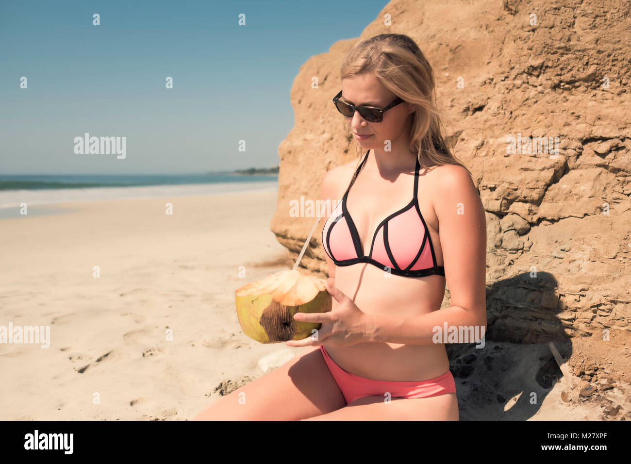 Young caucasian woman on vacation enjoying coconut water at a beach in Mexico Stock Photo