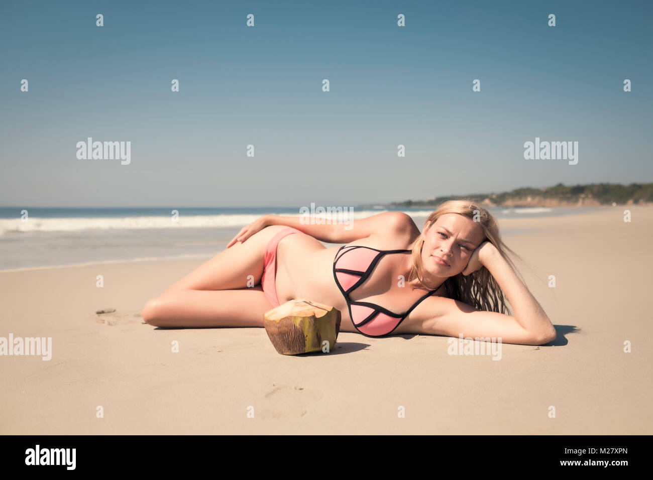 Young caucasian woman enjoying a vacation day with a fresh coconut at a beach in Mexico Stock Photo
