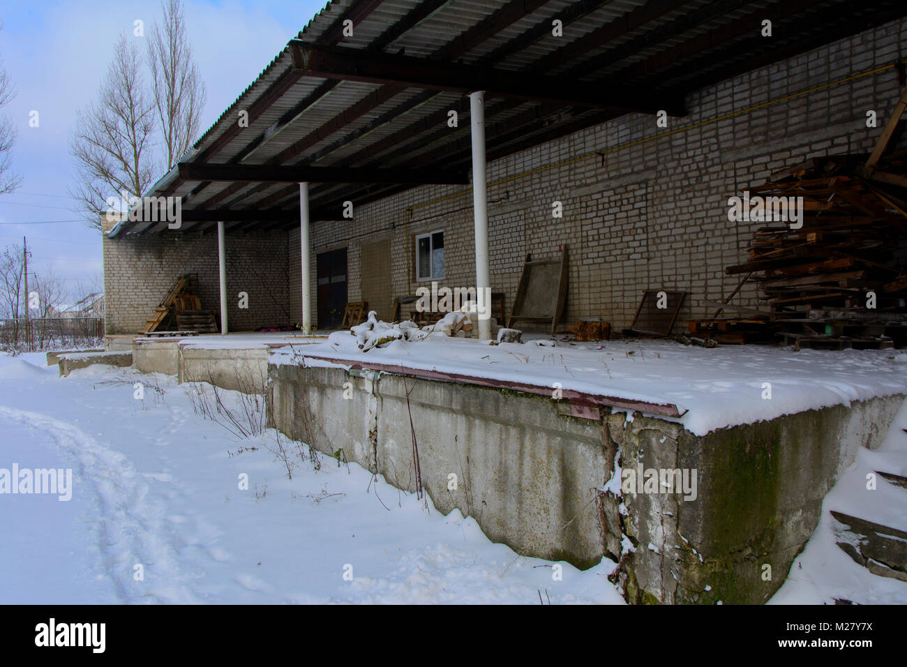 A platform for loading and unloading materials of the destroyed and abandoned bakery building against the background of winter trees and a blue cold w Stock Photo