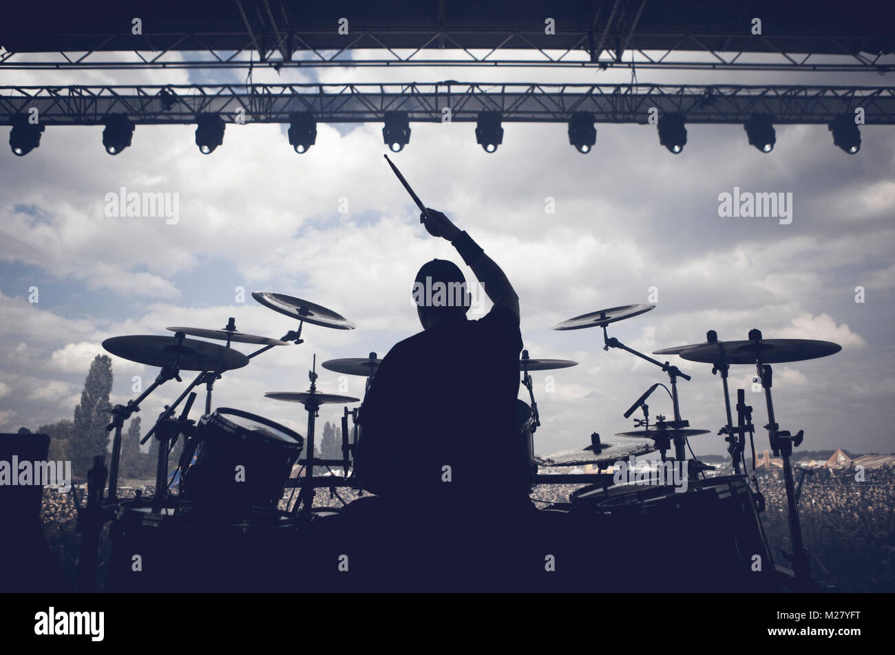 A drummer is raising one hand with a drum stick in the air in ...
