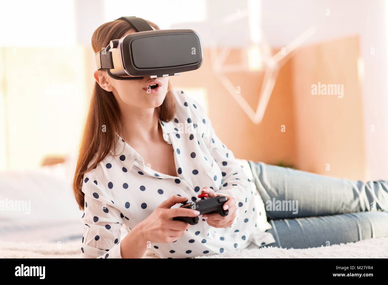 Fascinated young woman dedicating to VR game Stock Photo