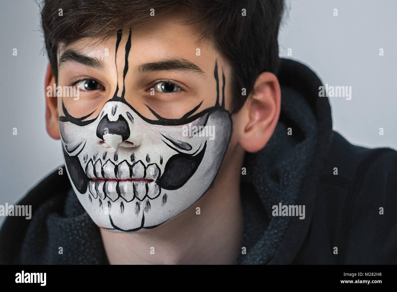 Portrait of a beautiful teenager with a makeup on his face in the style of Halloween. Close-up photo Stock Photo