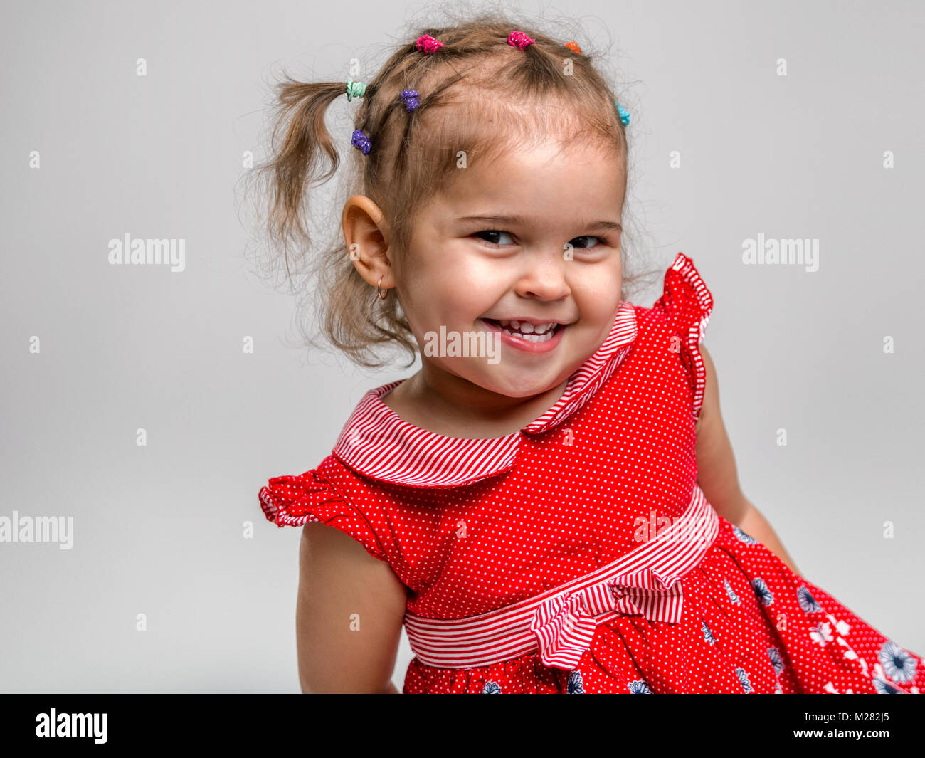 Portrait of a beautiful little cheerful girl on a white background. The ...