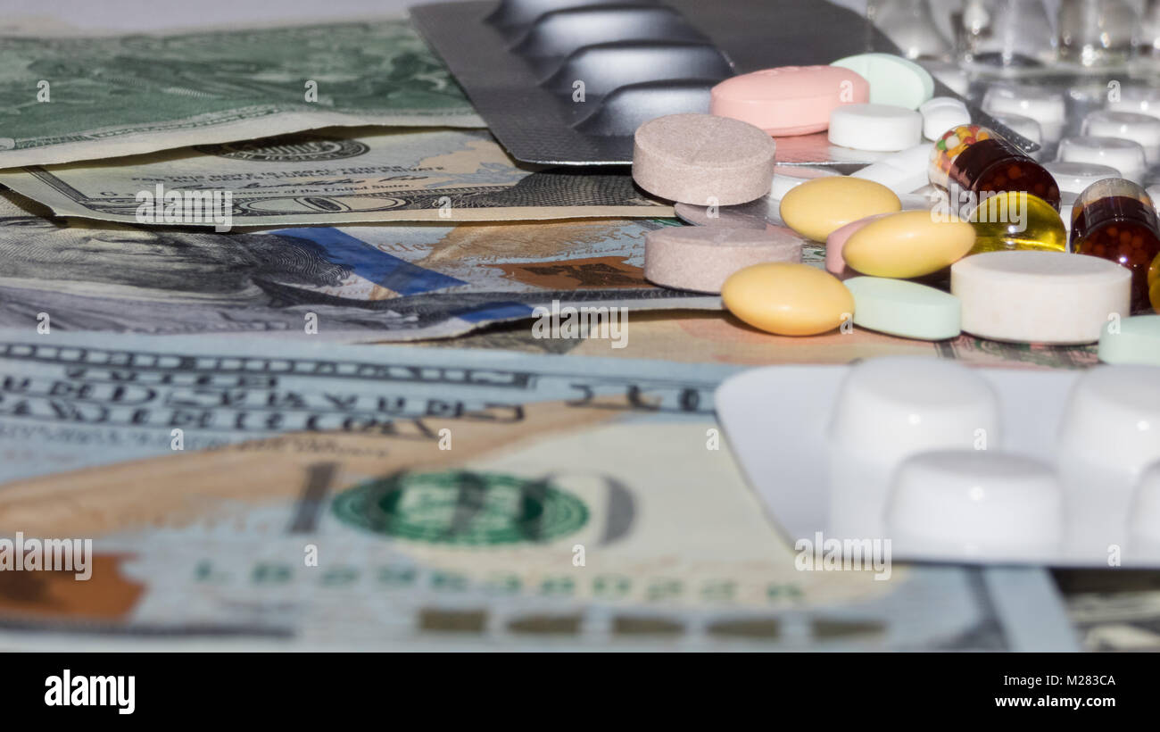 a bunch of medical pills of different colors on a dollar bills, blurry photos Stock Photo