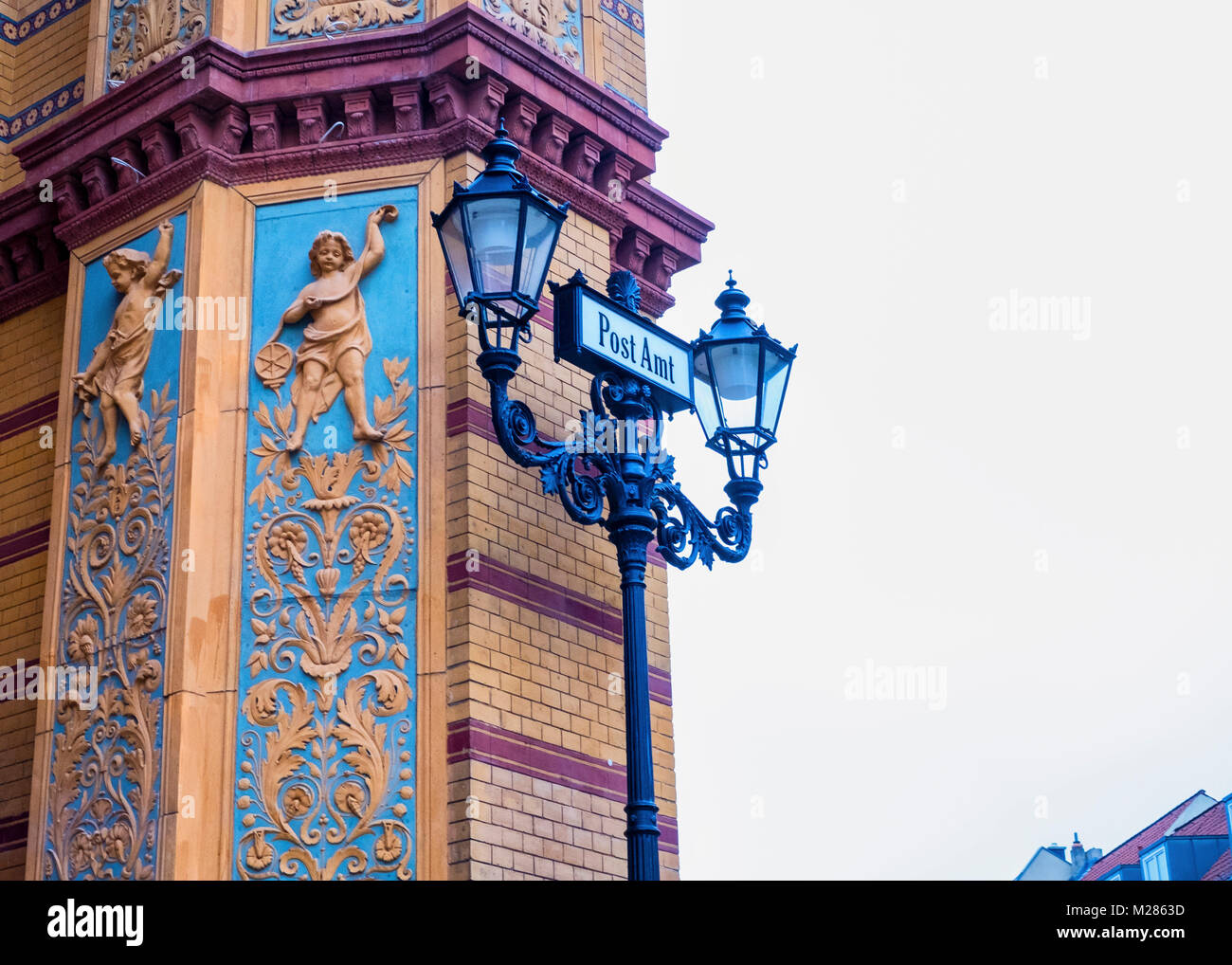 Berlin, Mitte. Old Post Office Building, Historic old listed building exterior,Yellow Brickwork,sculptural detail and old lamppost with Post Amt sign Stock Photo