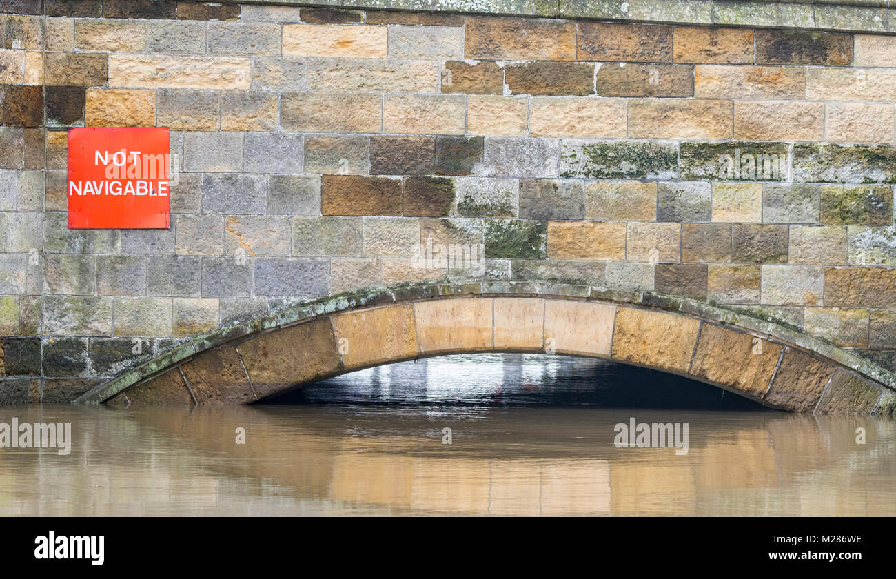 Old stone bridge at high tide at very high water with a Not Navigable sign on the River Arun in Arundel, West Sussex, England, UK. Stock Photo