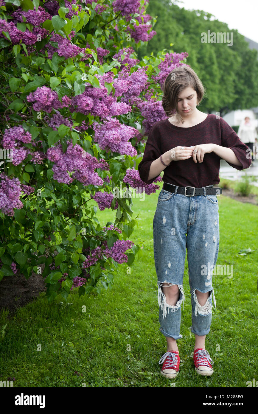 Pensive girl posing in lilac bushes in the park Stock Photo